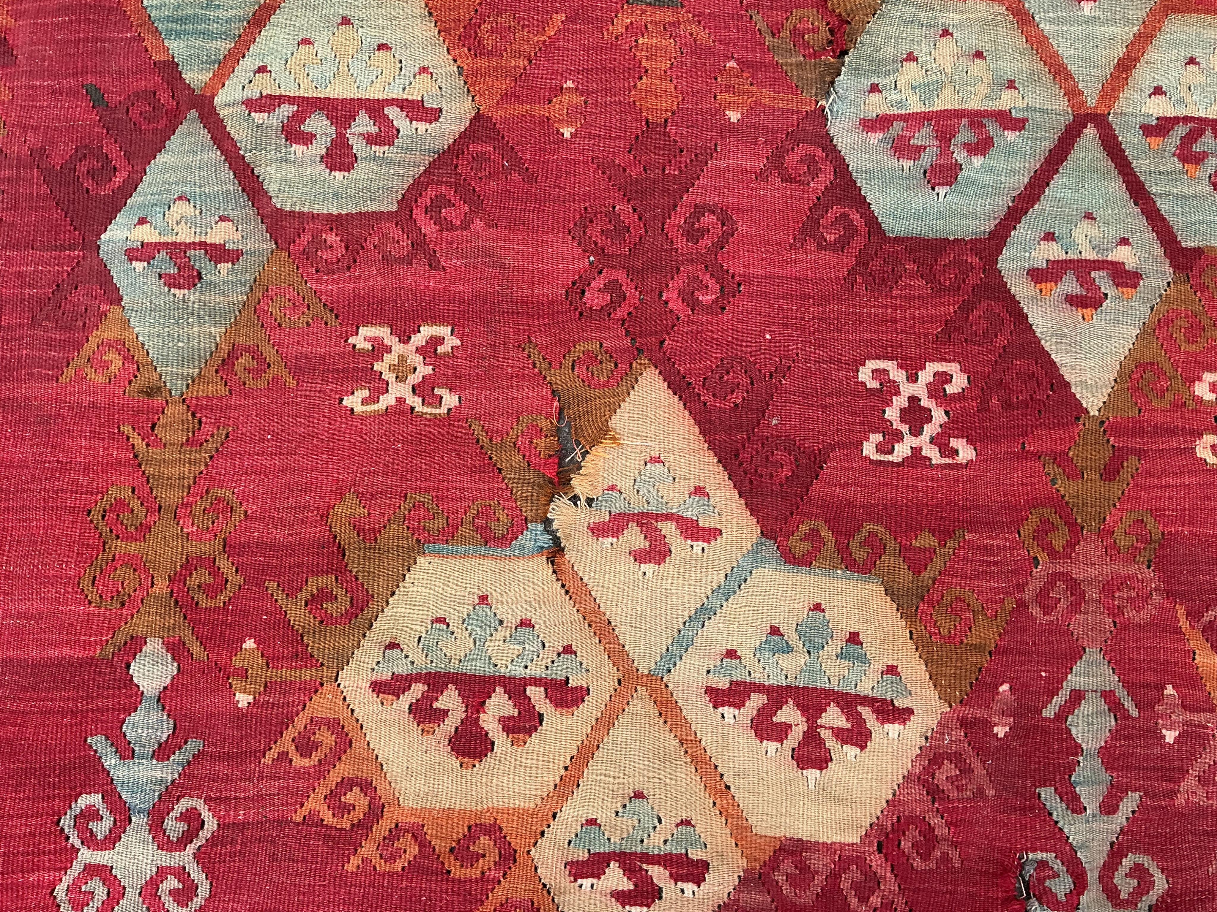A Turkish Anatolian Kilim polychrome flatweave carpet, woven with geometric lozenges, on a pink field, 350 x 273cm